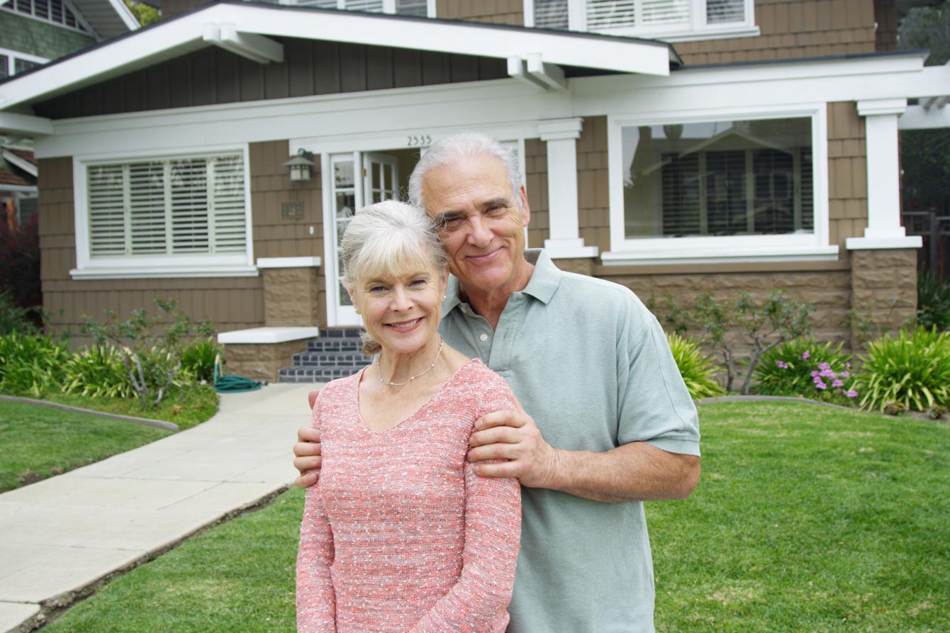 Senior couple standing in front of a small house