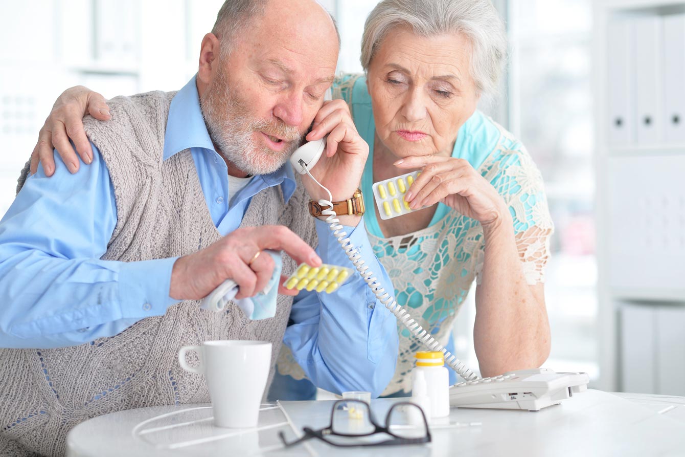 Elderly couple with table full of pills on the phone receiving instructions