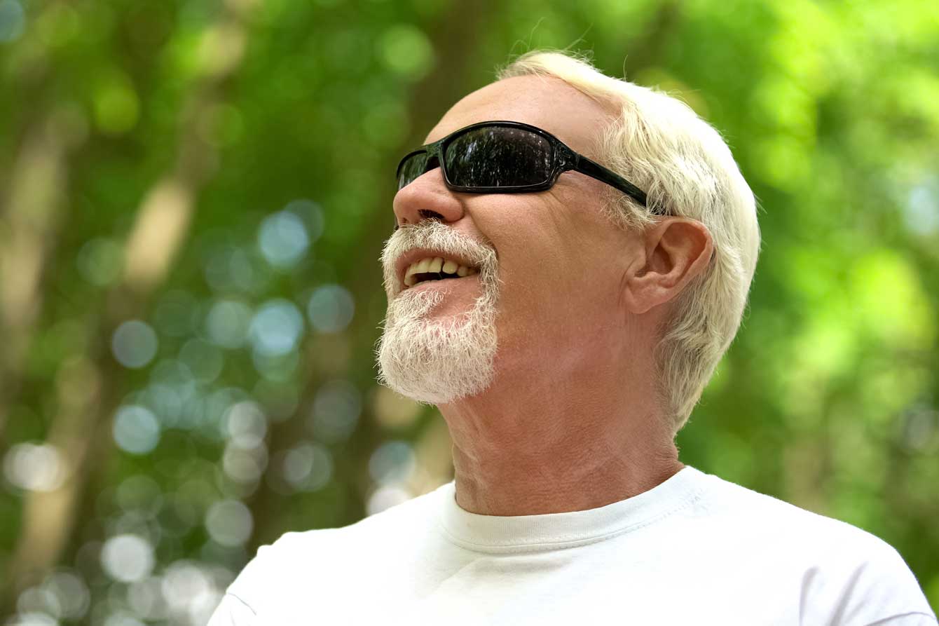 Visually impaired man in sunglasses listens to nature sounds with heightened senses