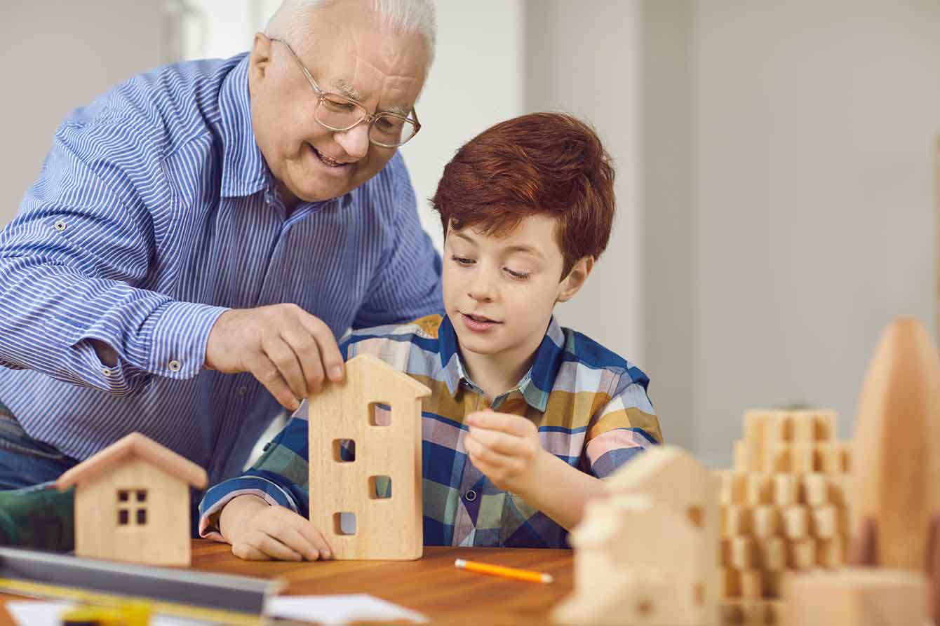 Grandfather and grandson build a wooden model home together