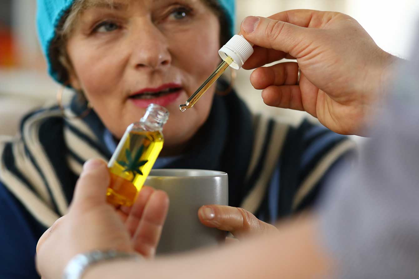 Close-up of an elderly woman receiving a small bottle of CBD oil