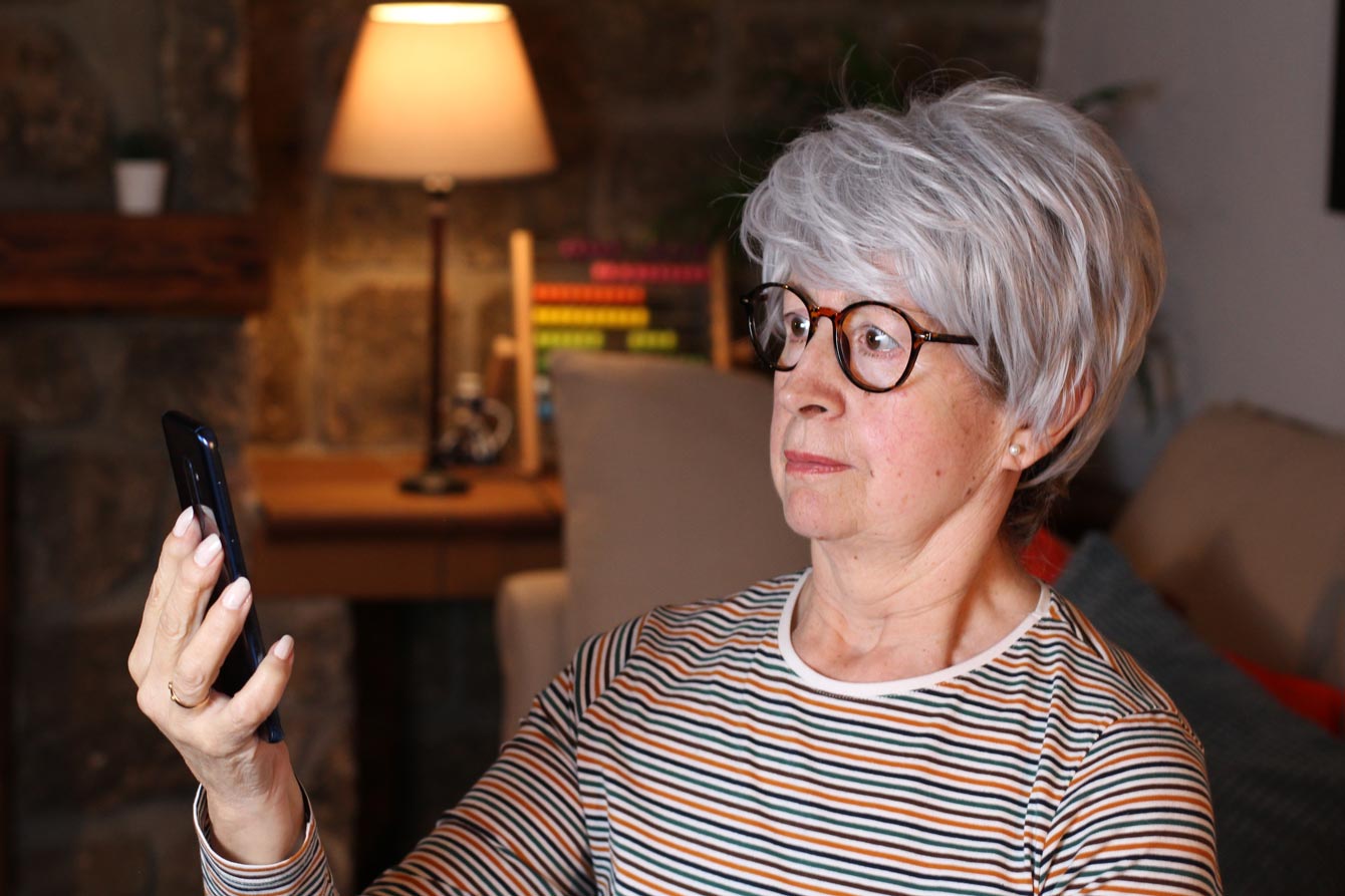 Confused older woman staring at her phone