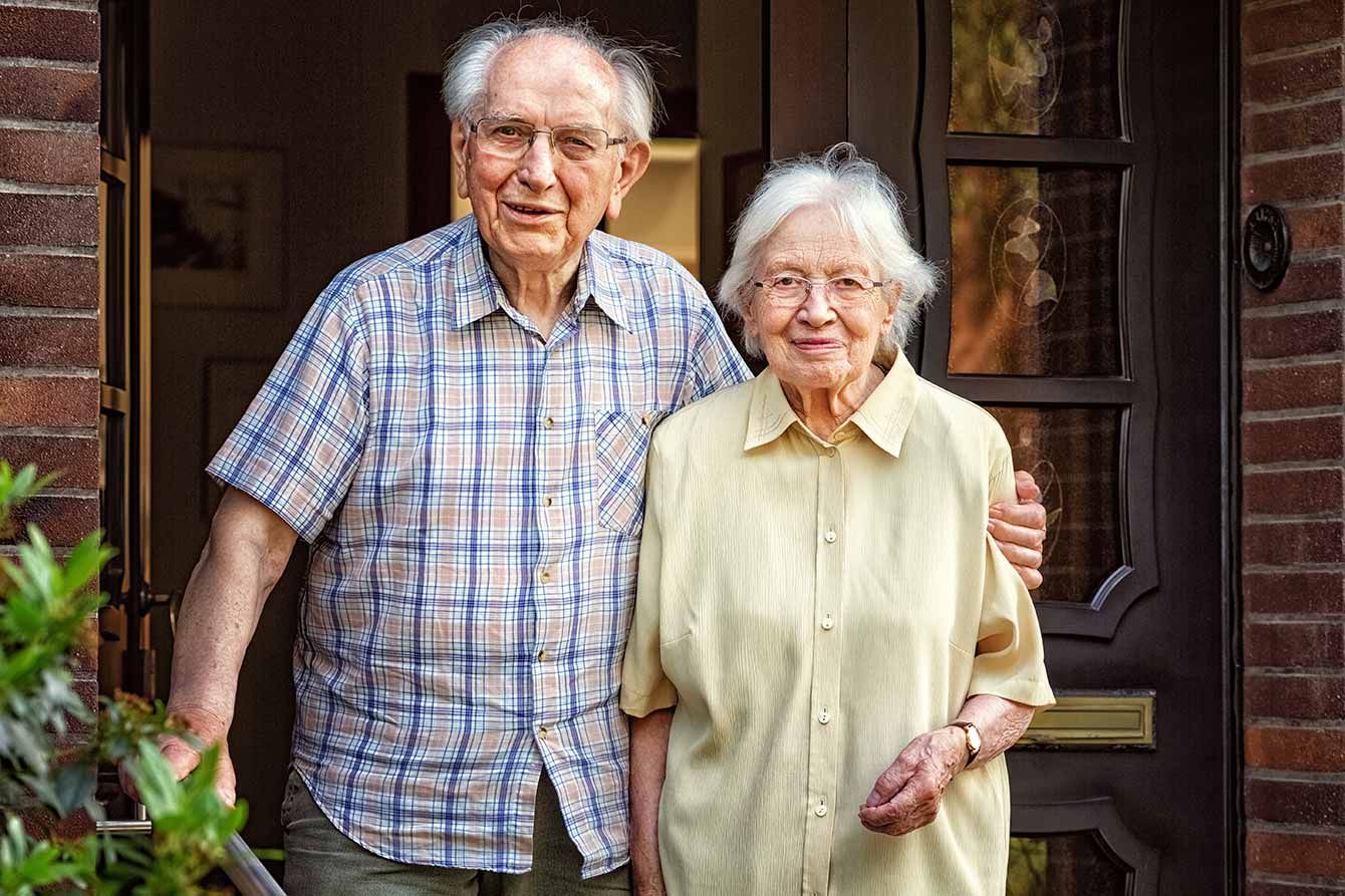 Elderly couple standing at their front door