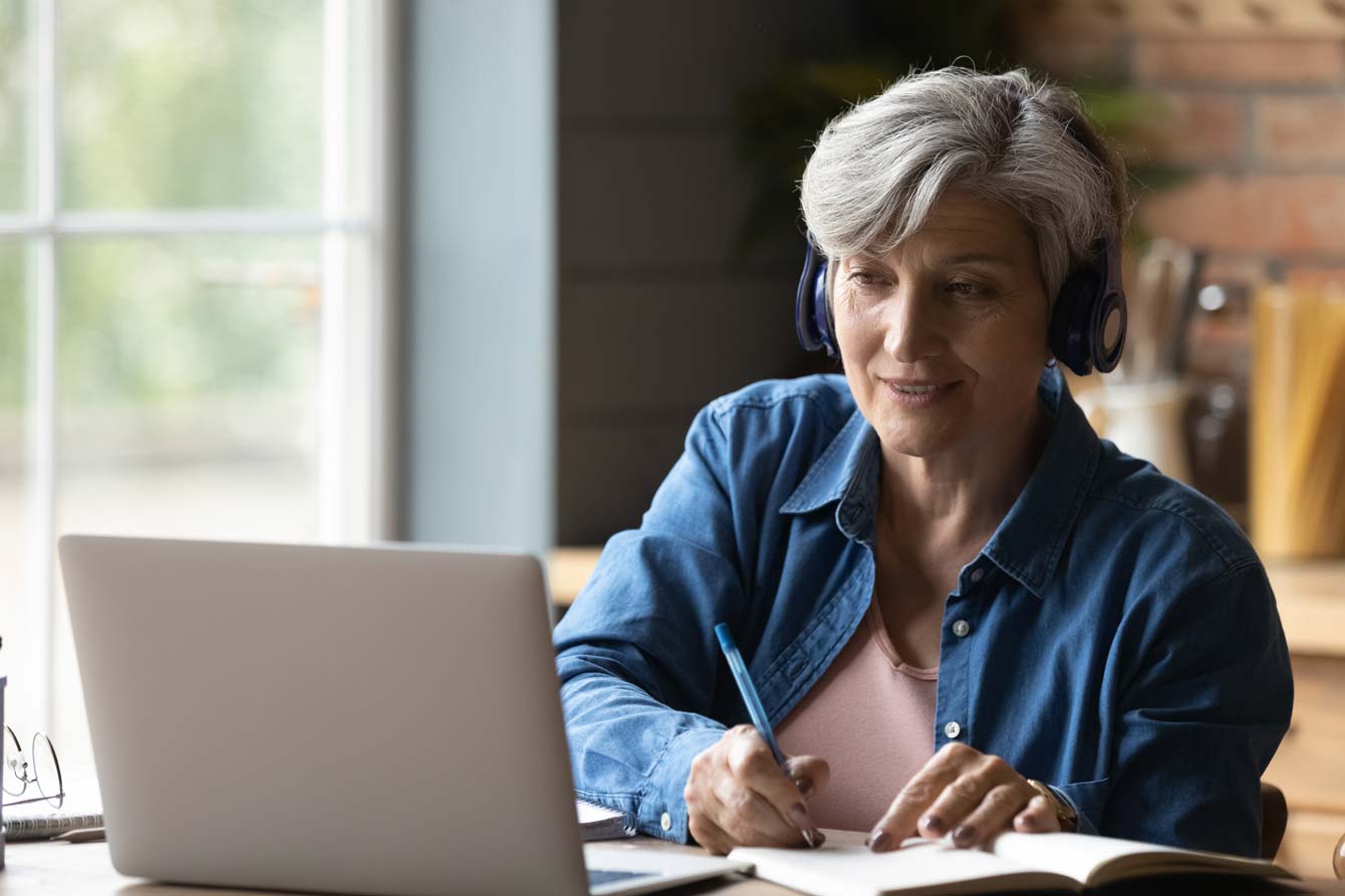 Woman in her 60's at laptop takes an online learning class