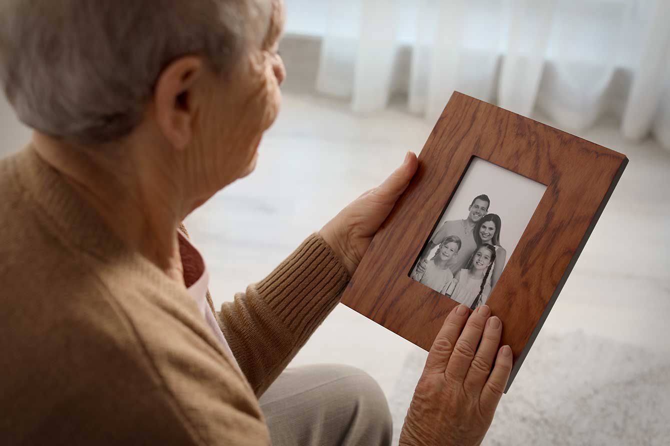 Elderly woman holding framed family portrait