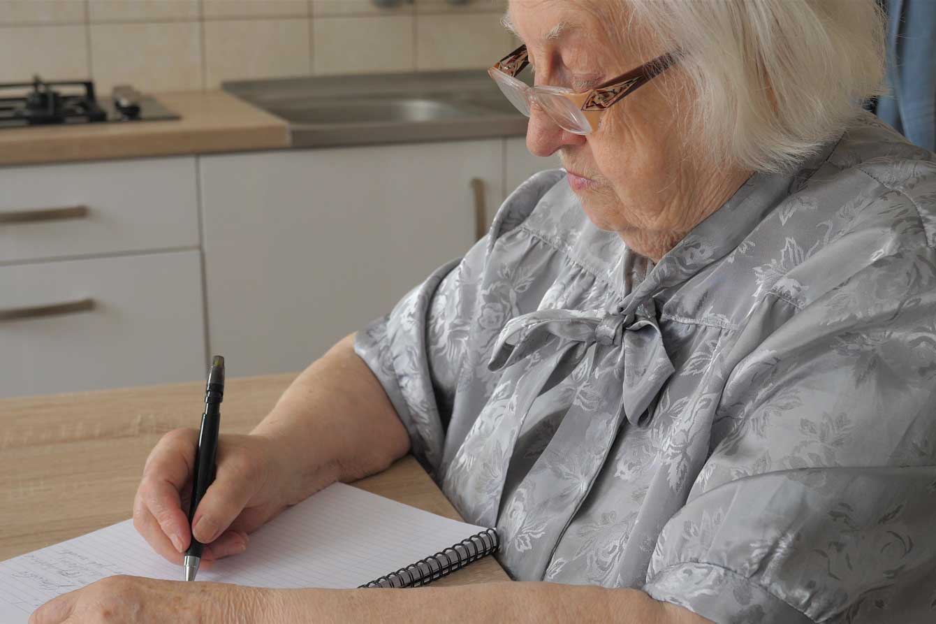 An older woman writes a letter