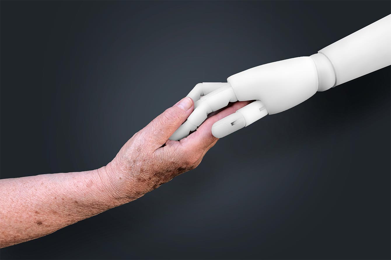 Older hand holds a white robot's hand
