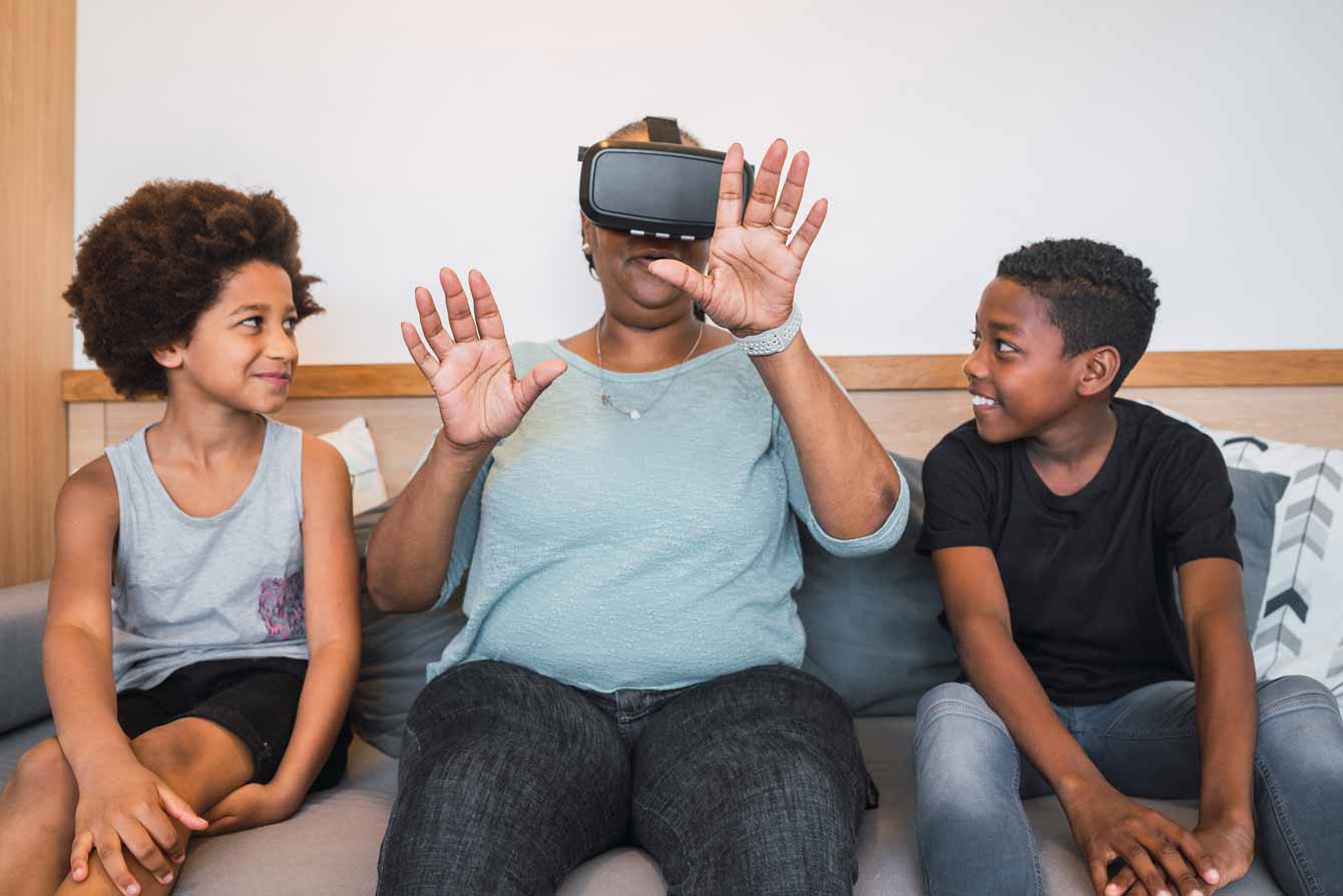 Grandmother and grandchildren playing together with VR headset