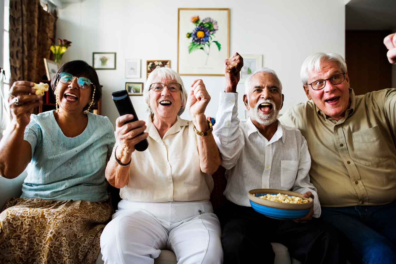 Group of happy seniors watching TV together