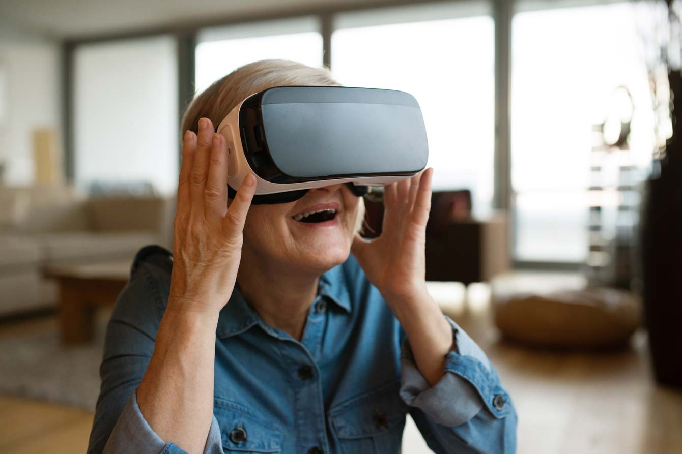 Senior woman wearing virtual reality goggles at home