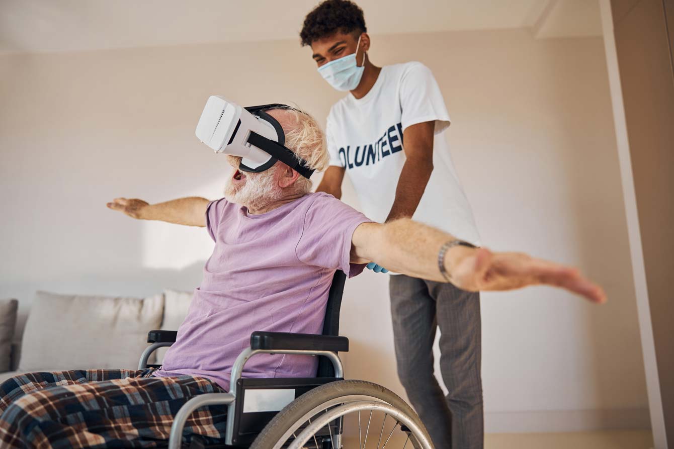 A senior man in a wheel experiences flying in virtual reality