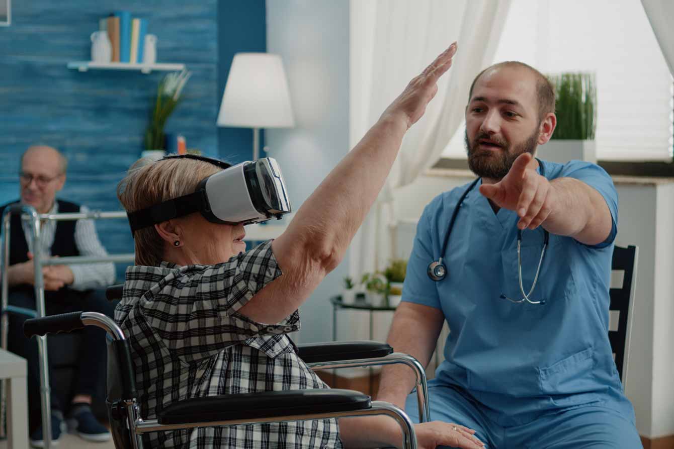 A woman in assisted living uses virtual reality goggles to help exercise and reduce pain