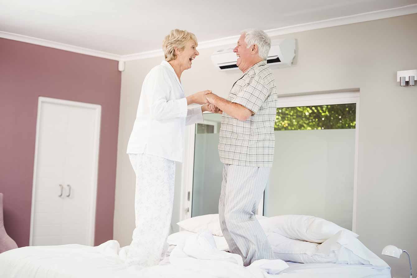 Cheerful senior couple jump on the bed