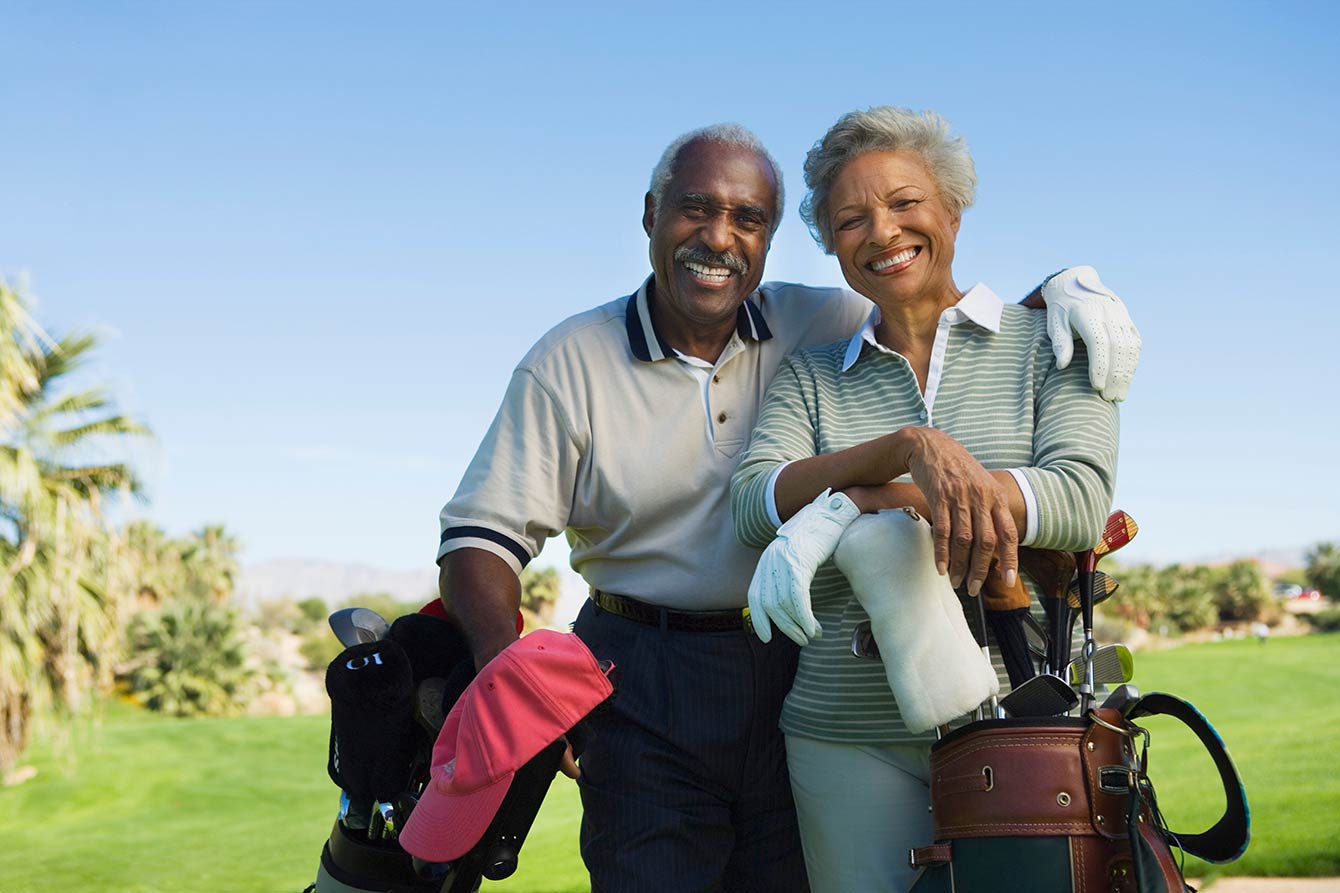 Smiling black american seniors with golf clubs on a golf course
