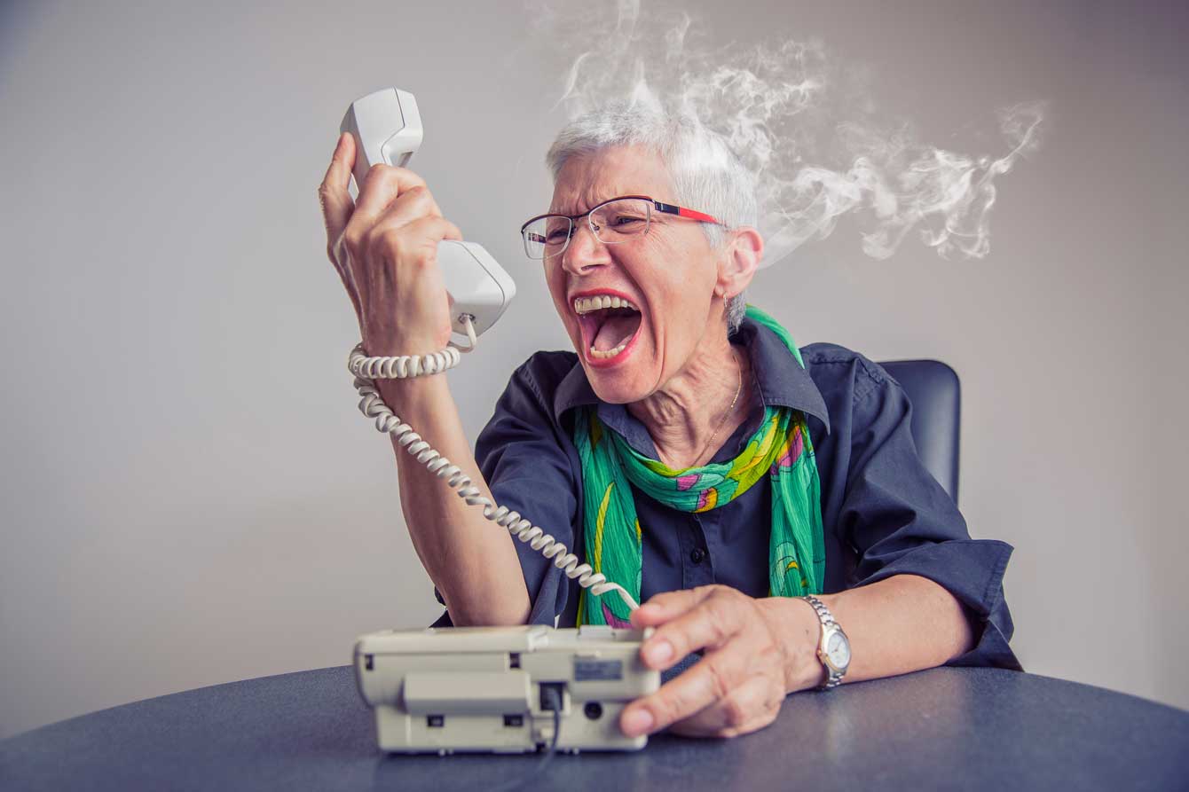Angry older woman screams into phone with her white hair turning into smoke