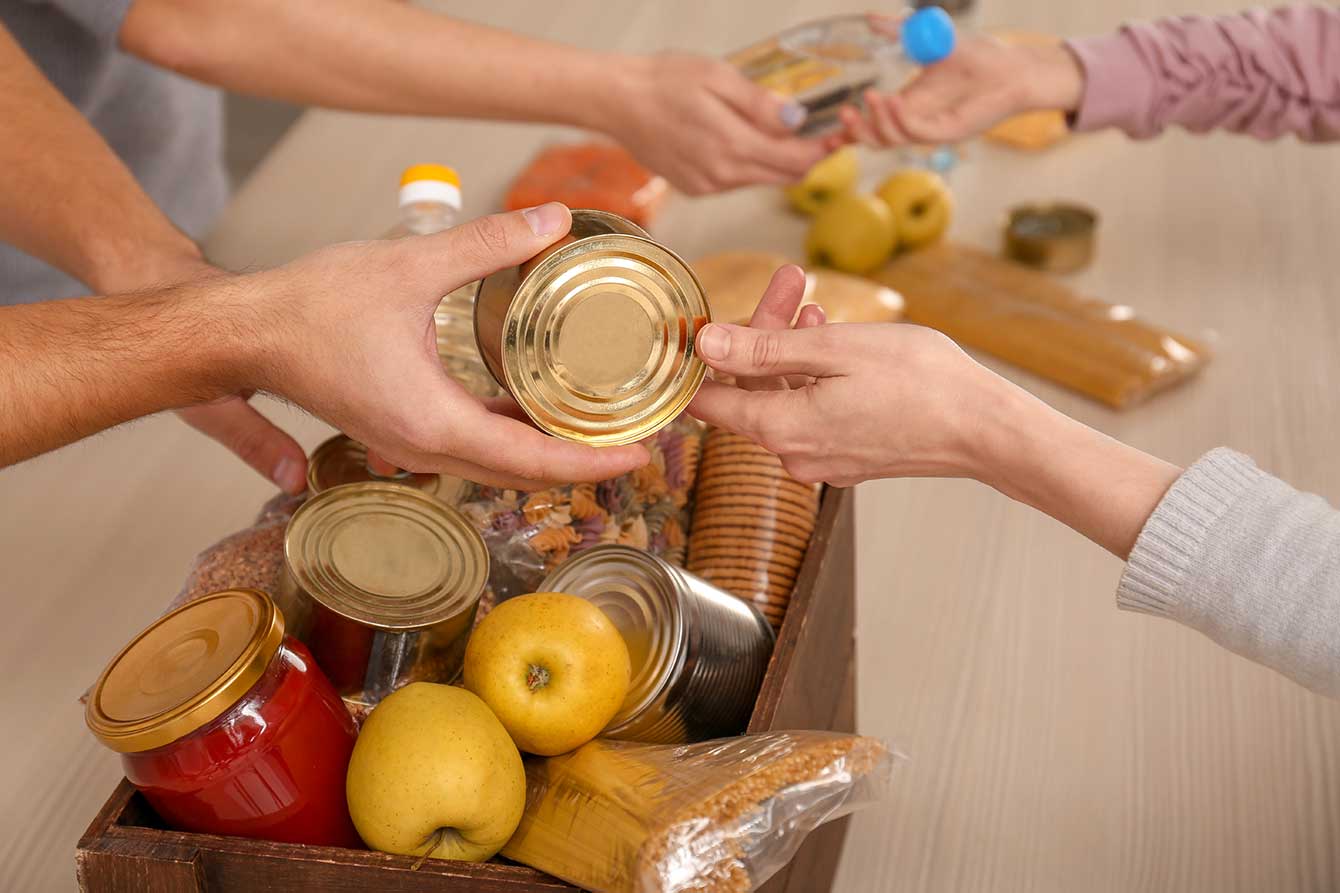 Close-up of volunteers placing food into a donation box