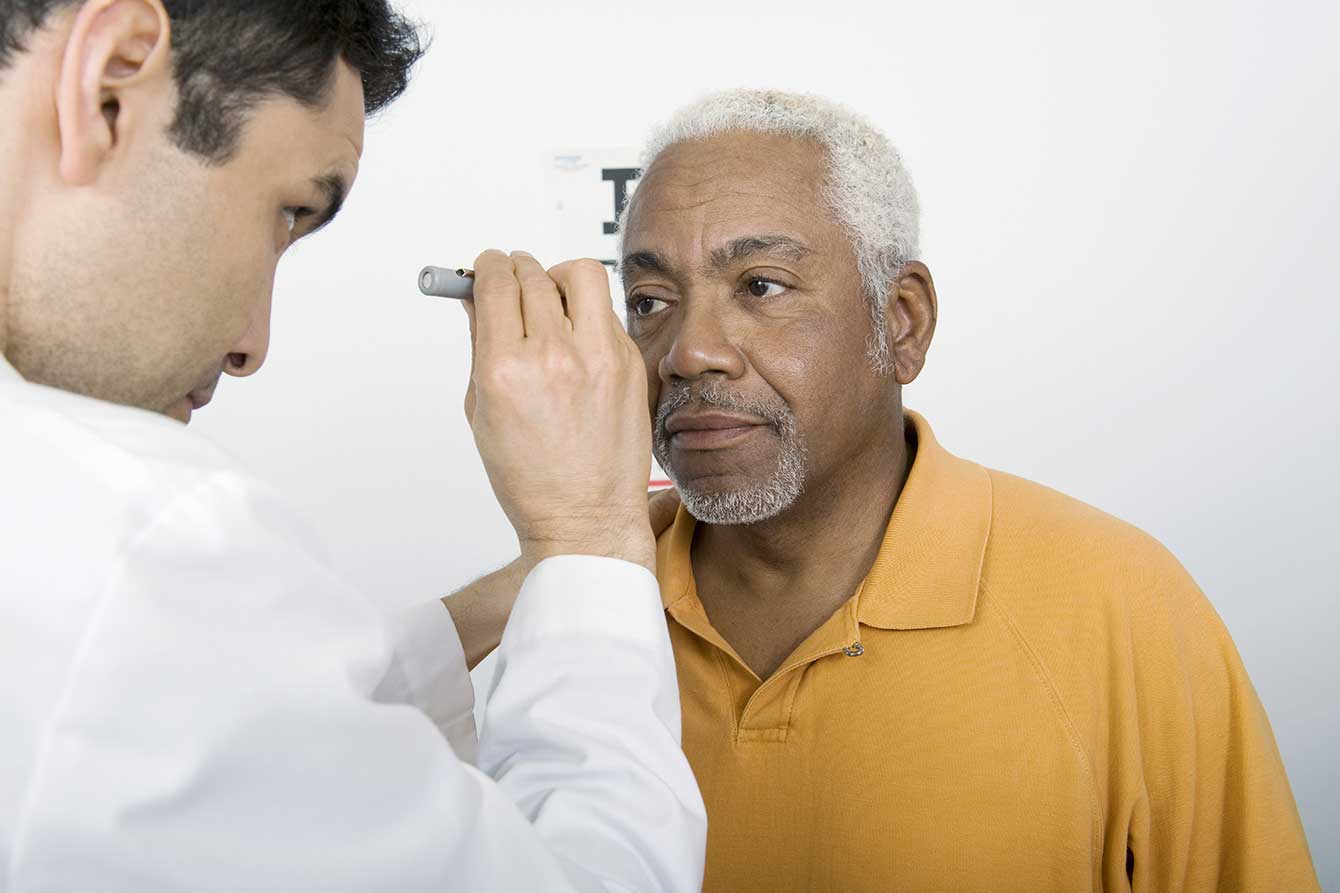 An older black man gets his vision checked by a doctor