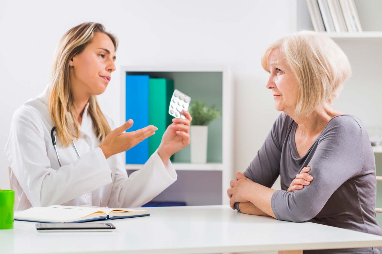 A senior female sits with female doctor frustrated with her advice to take pills