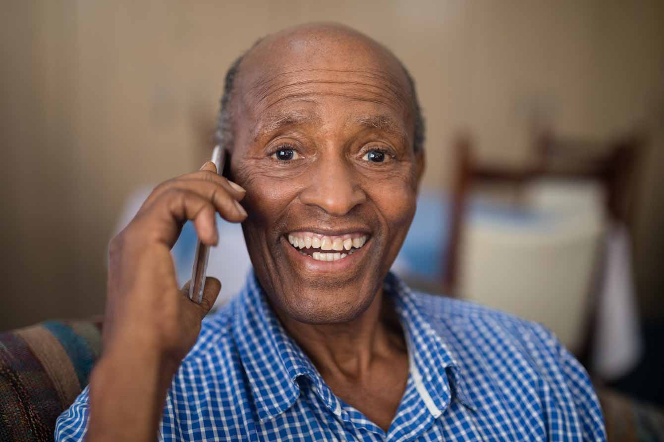 Cheerful senior black man speaks on cell phone