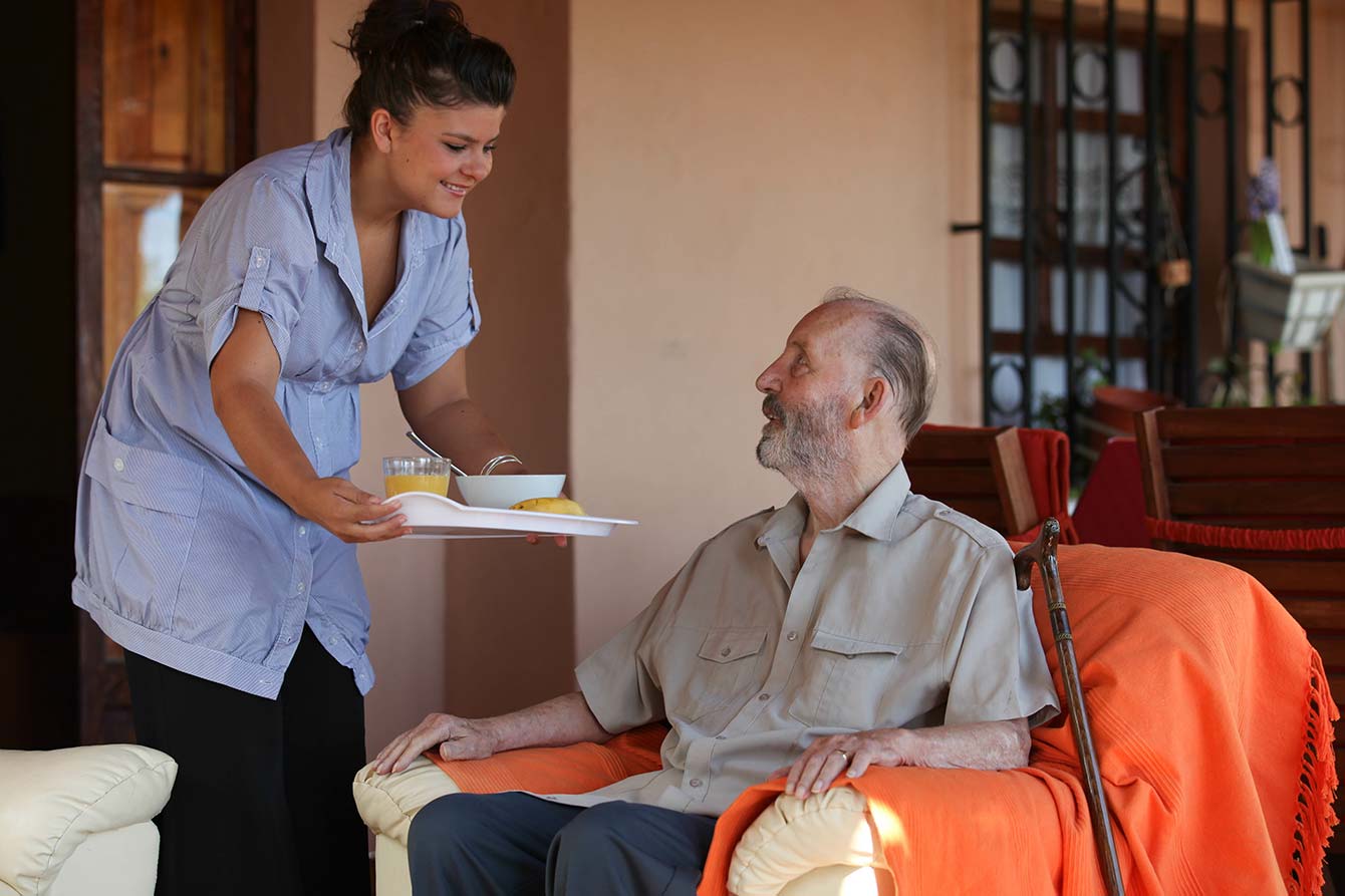 Nurse delivers food to injured senior in assisted living group room
