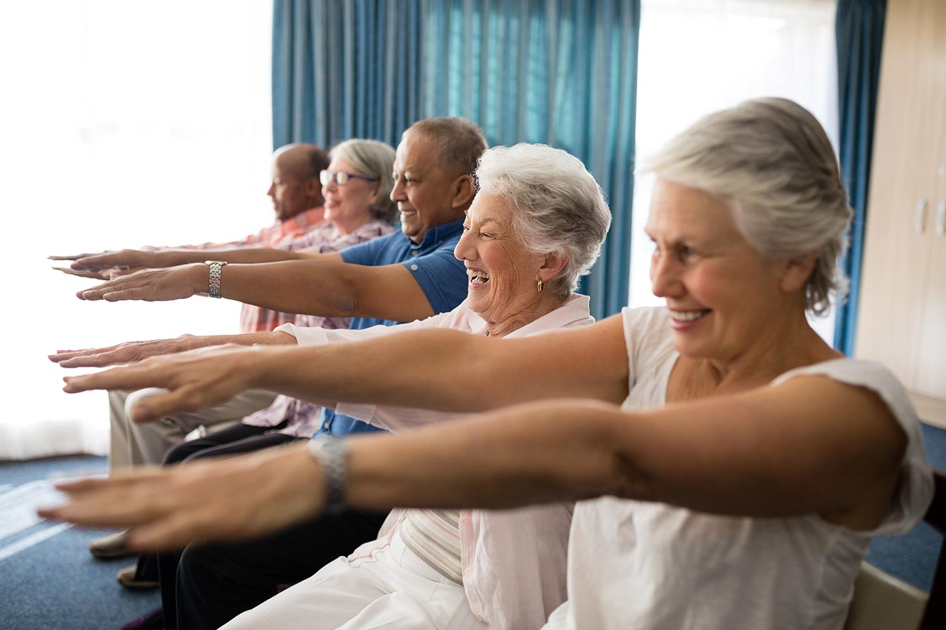 Cheerful seniors exercising with their arms raised