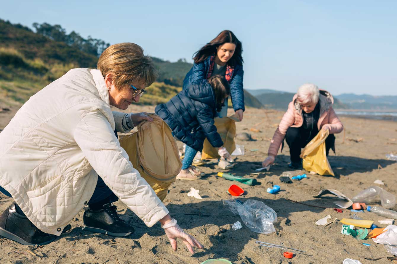 Group of senior female volunteers picking up trash on the beach