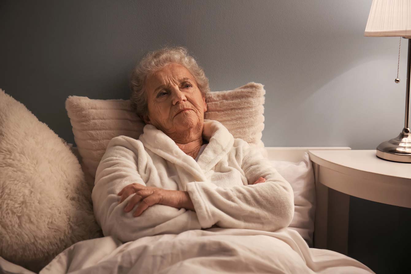 Older female struggles with insomnia while resting in her bed