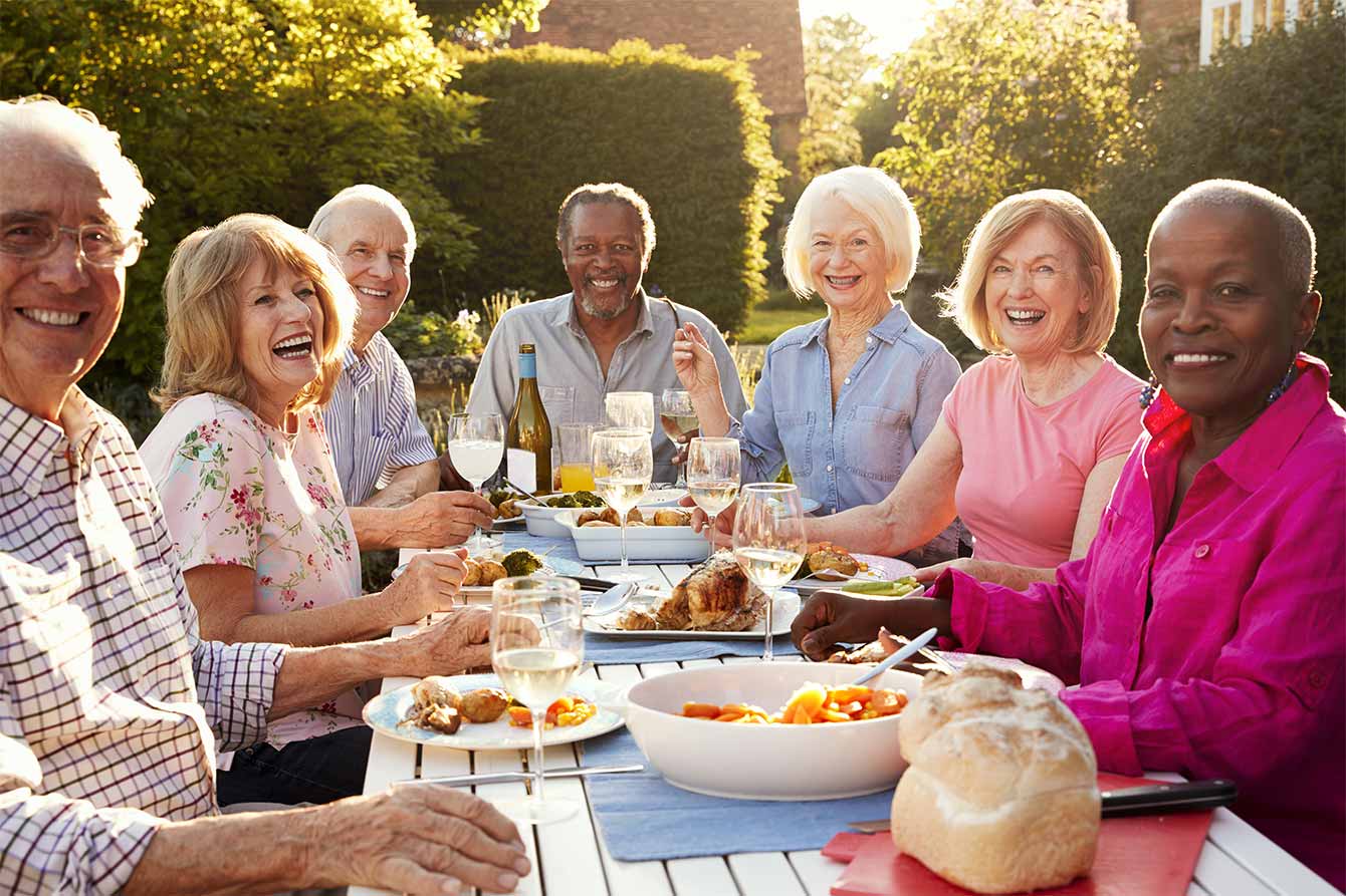 Portrait of senior friends enjoying outside dinner at home