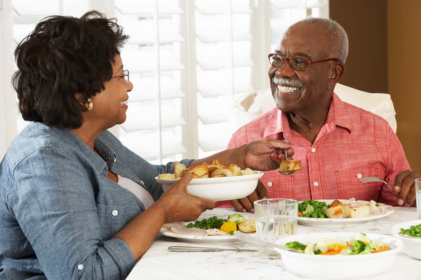 Senior African American couple enjoying healthy dinner at home