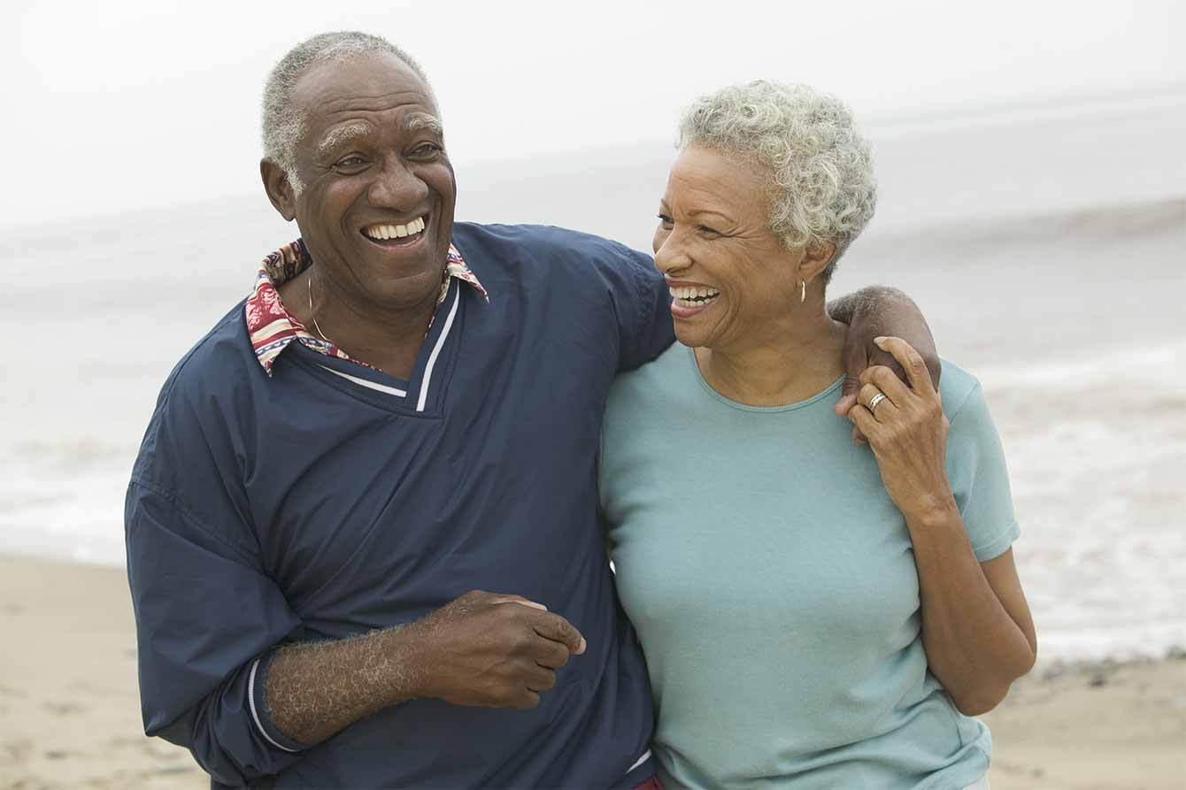 Cheerful African American mature couple with arms around each other at the beach