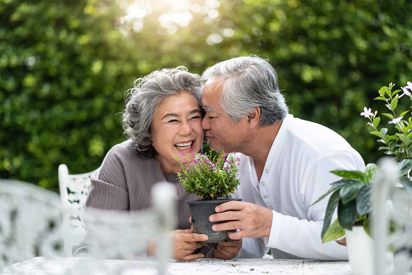 Happy Asian senior couple laughing and man kissing woman on cheek