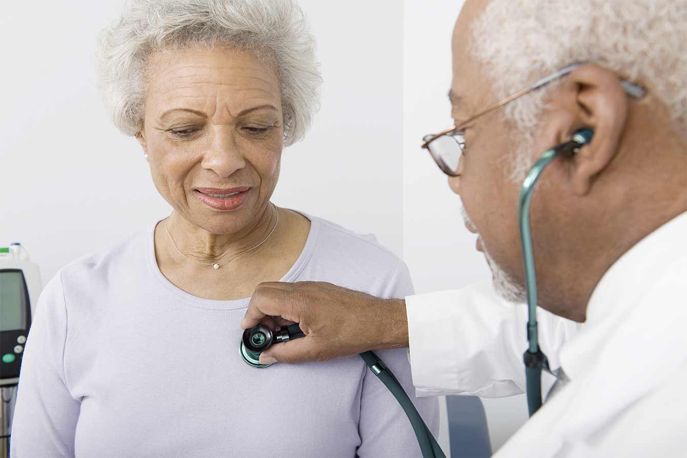 A doctor checker an older woman's heartbeat using stethoscope