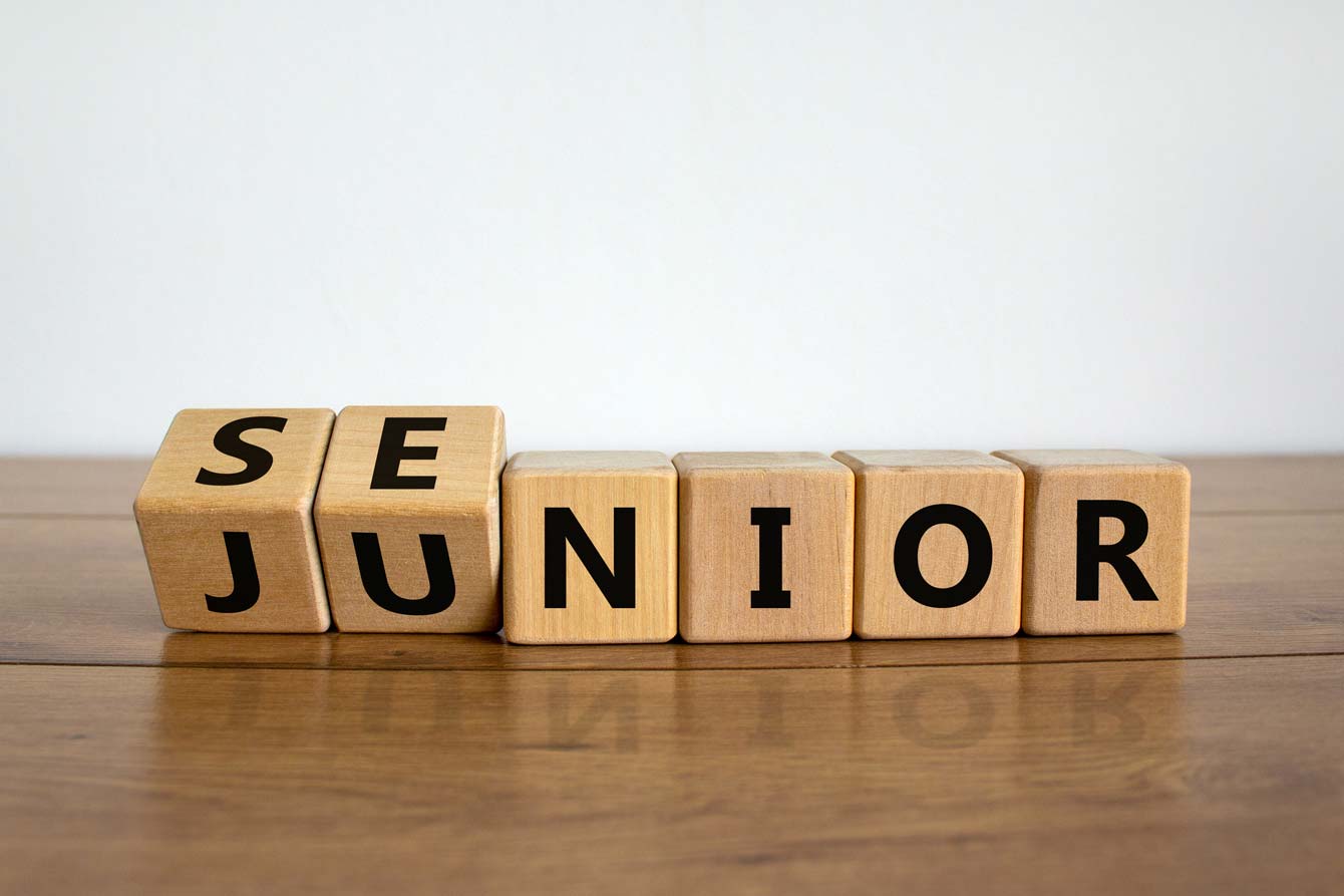 Small wooden blocks spell the word junior while rotating to show the word senior coming