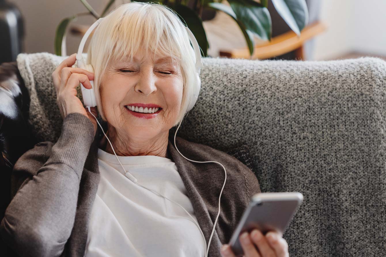 senior lady enjoying a podcast on her phone while lounging
