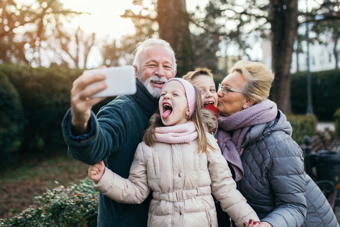 grandparents and young grandchildren take a selfie outdoors during winter