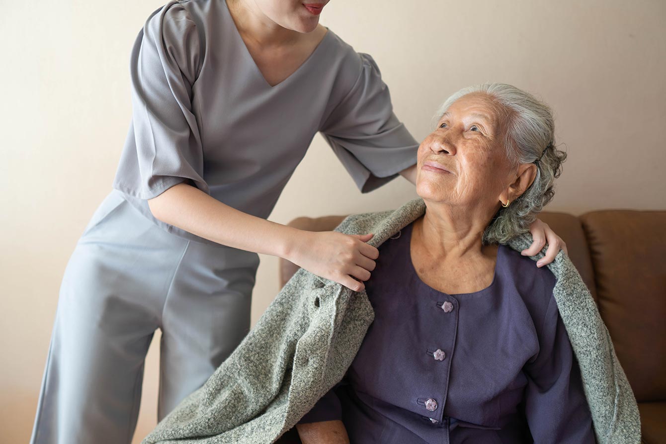 Happy elderly patient with friendly female nurse spending time together