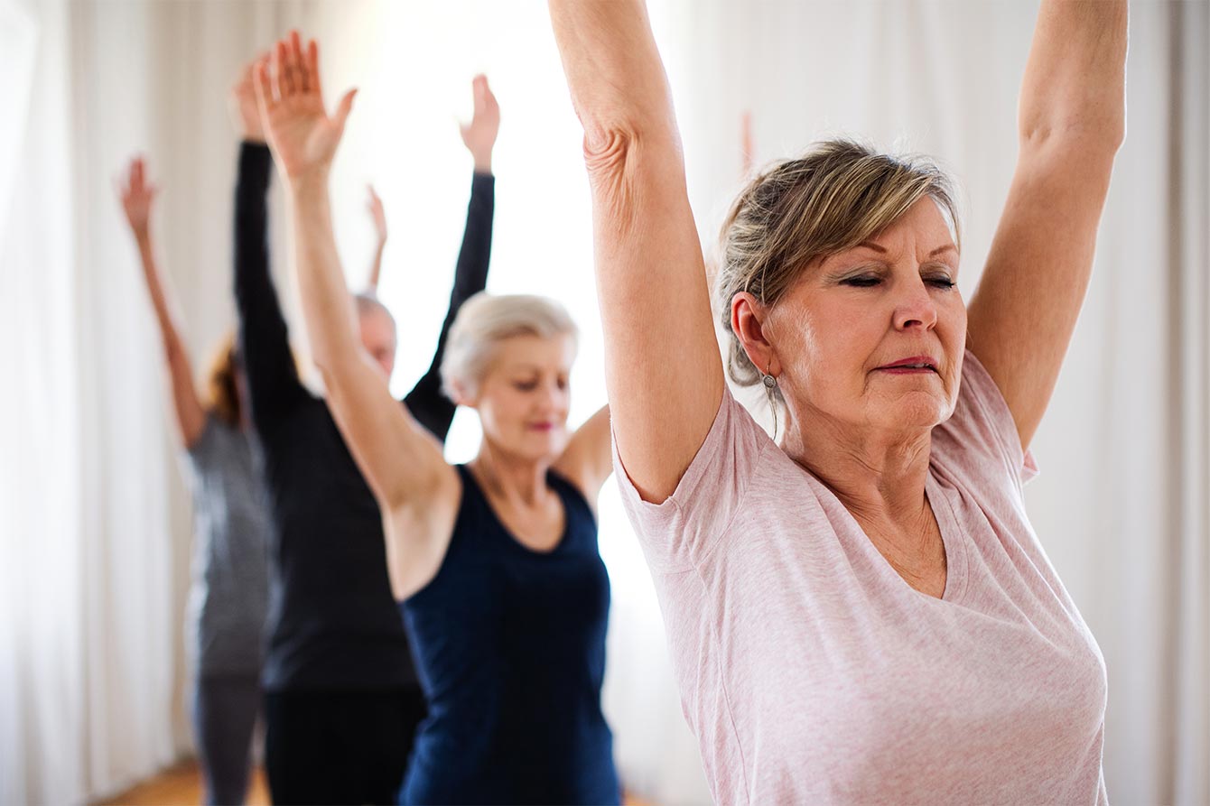 Group of senior adults doing yoga exercise in community center club