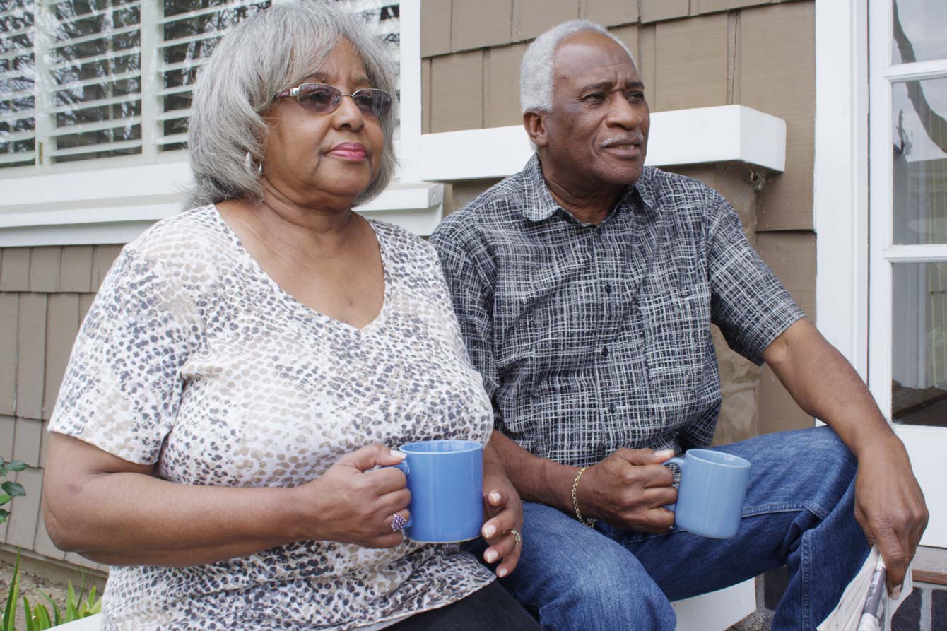 contented senior couple having coffee outside their home