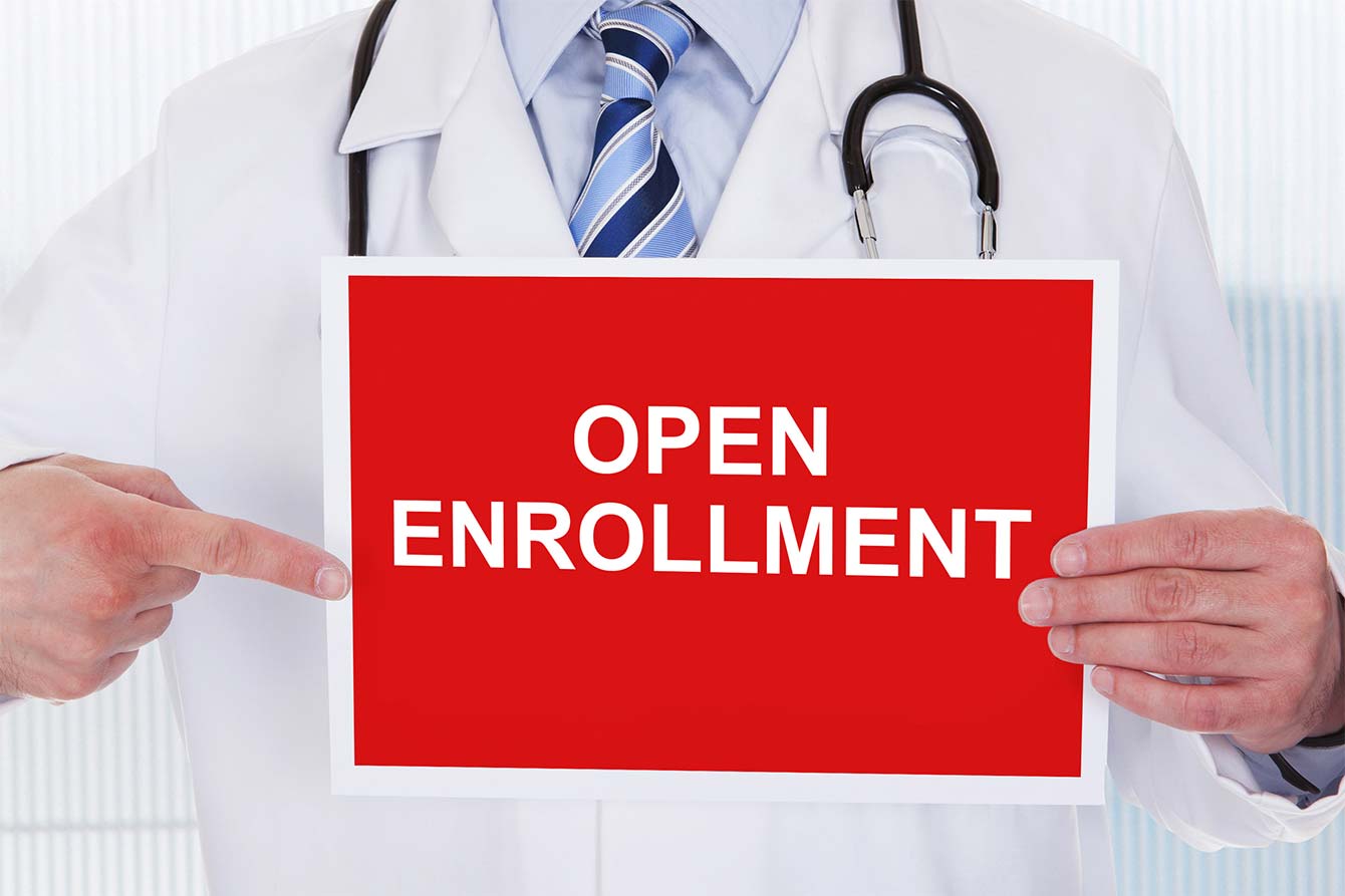 Doctor holds sign that says open enrollment
