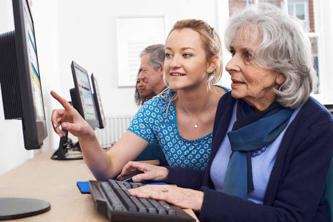 Young woman assists older woman at a computer