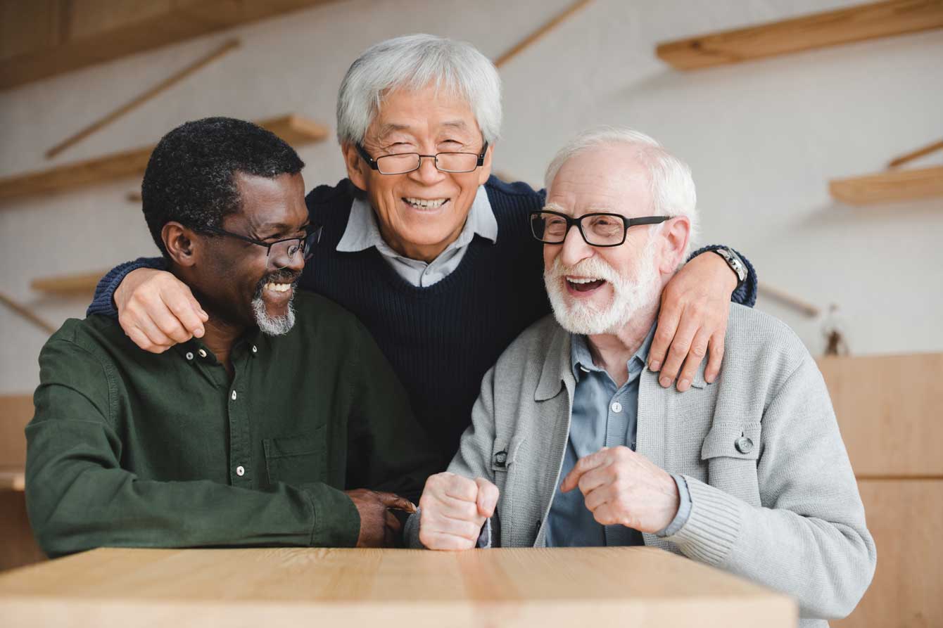 Three older men smile happily 