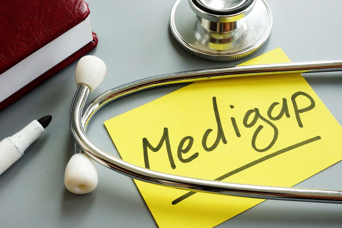 Medigap insurance written on a yellow sticky note next to a stethoscope