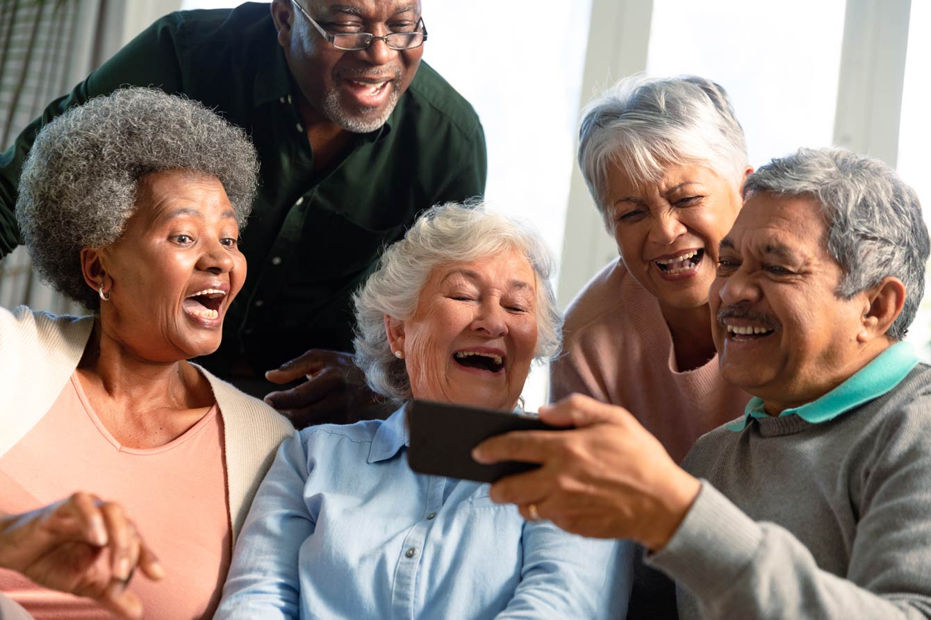 a group of senior friends watching a video on a phone