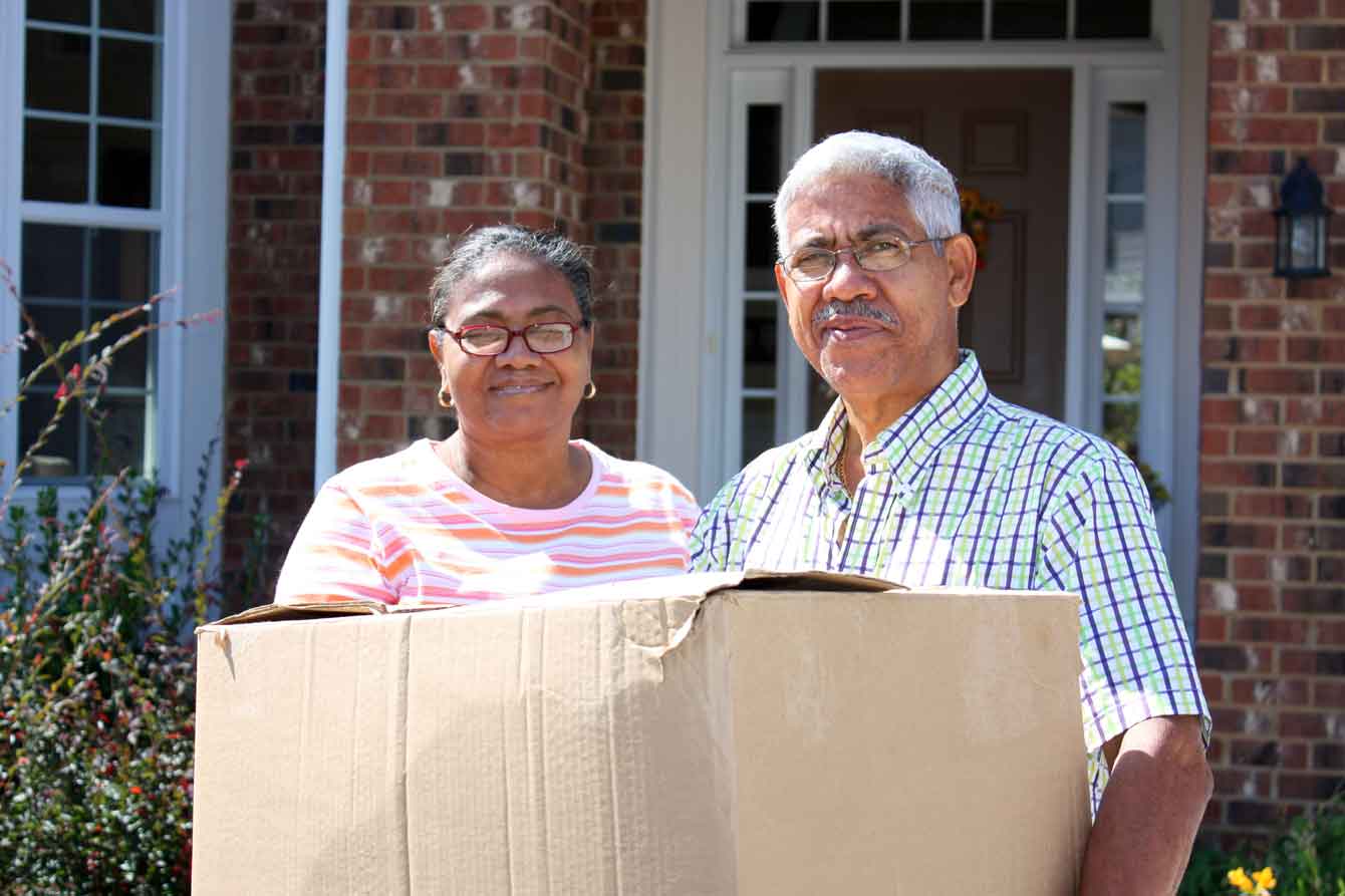 Senior latino couple holds moving boxes
