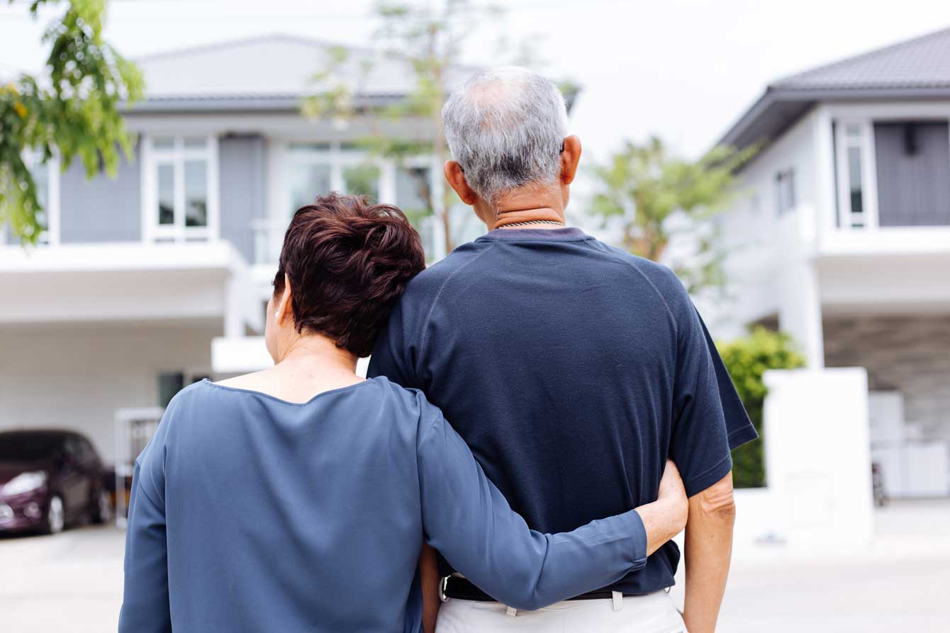 senior couple from behind looking at front of house and car