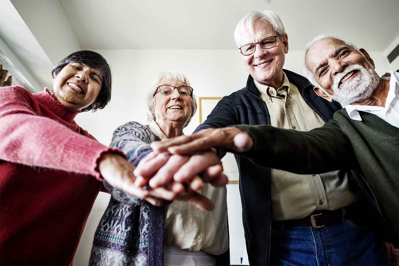 A group of happy senior friends with their hands on top of each other