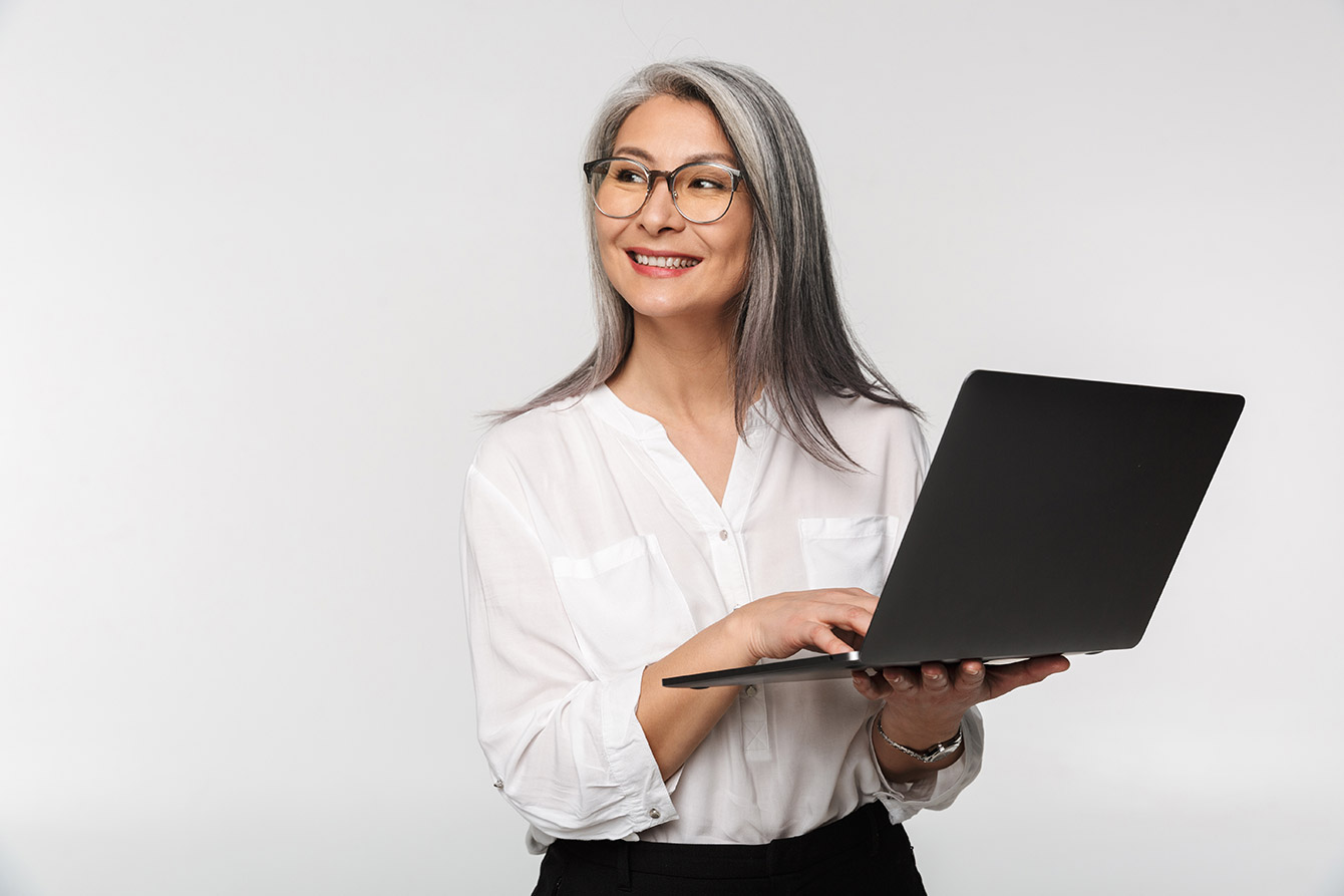Female senior standing and holding a laptop with both hands