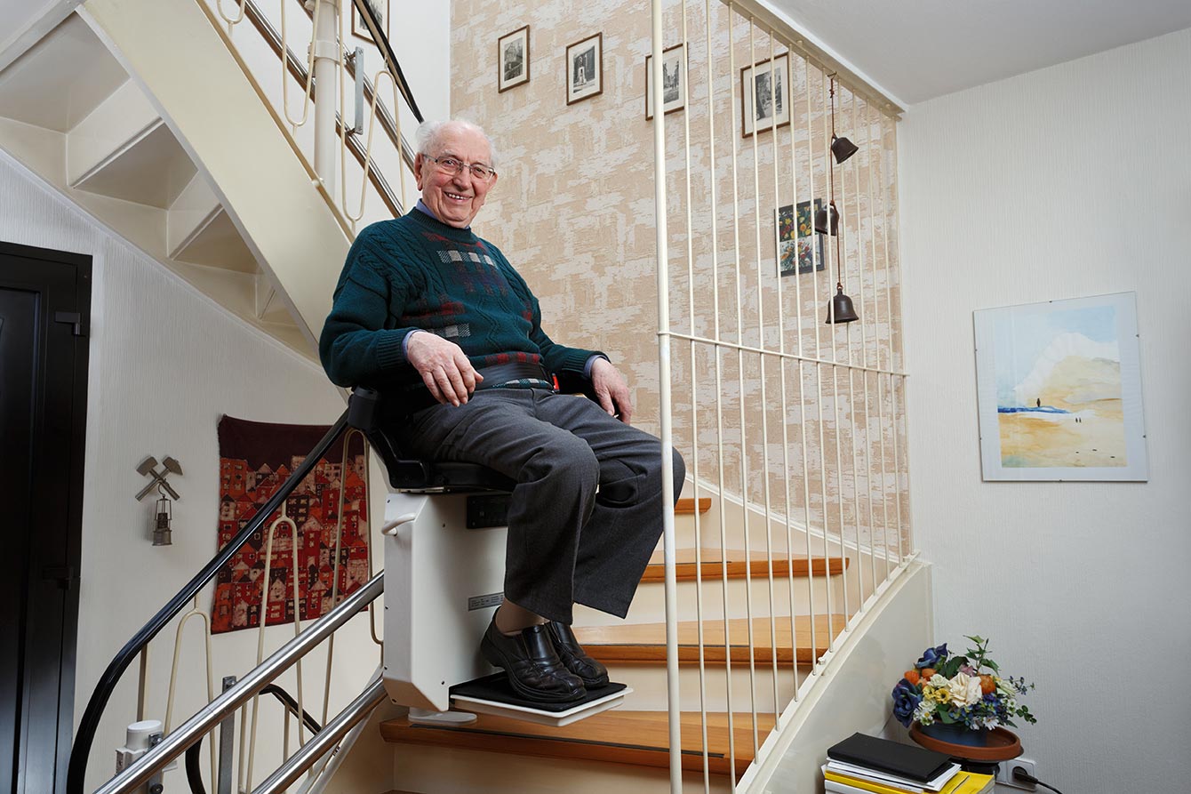 Older man uses a stair lift in his home