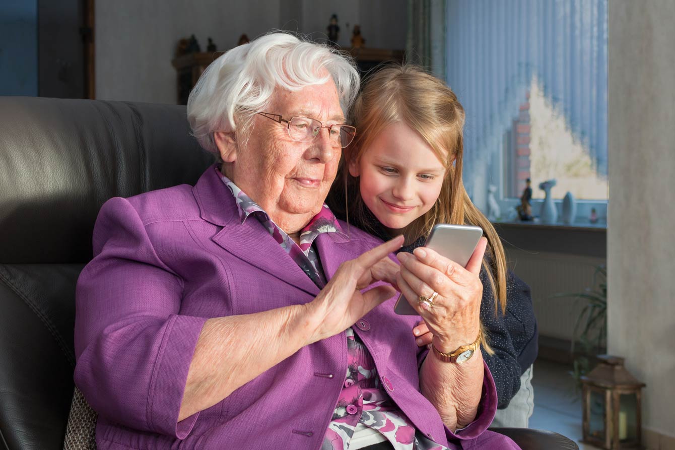 senior grandmother and young granddaughter lounging while surfing on the phone