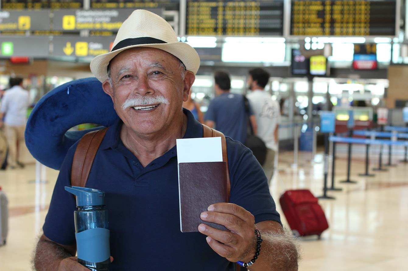 Senior latino man posing in the airport before boarding plane
